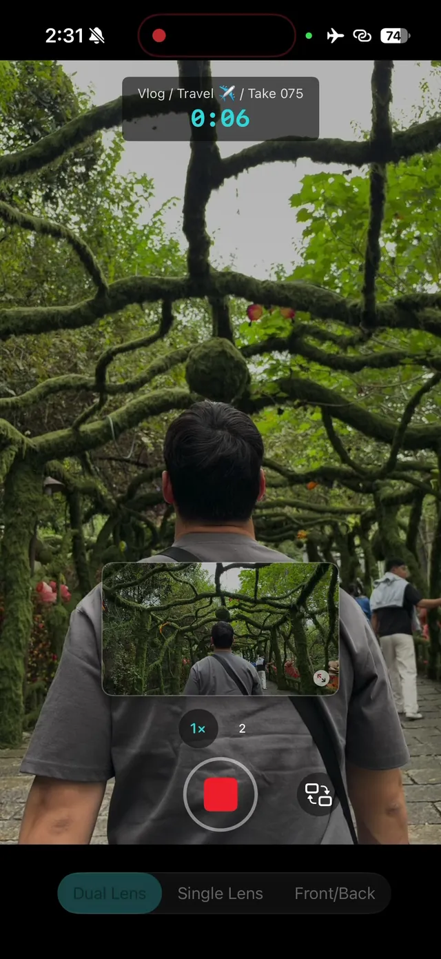 ContentCam recording in Dual Lens mode behind a man walking through a tunnel of moss-covered branches, the landscape preview in a small tile